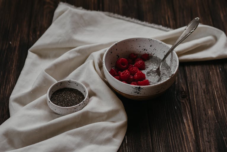 Delicious chia pudding topped with raspberries on a rustic wooden table.