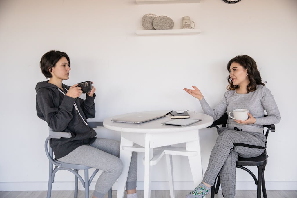 Two women enjoying a casual conversation with coffee in a cozy indoor setting, enhancing connections.