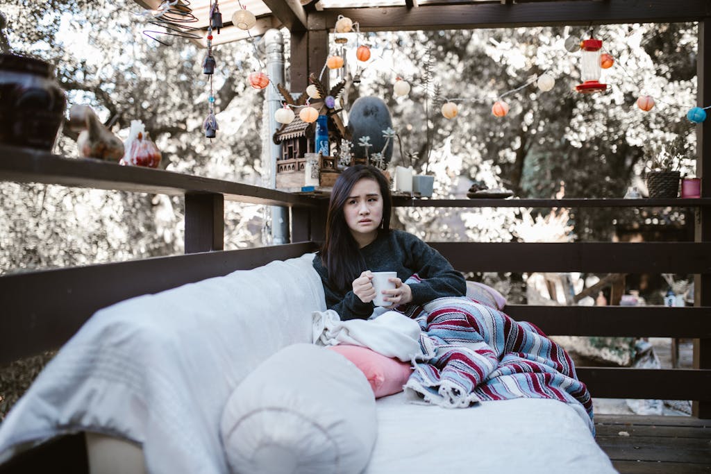 Woman enjoying a quiet afternoon with tea on a patio, wrapped in a colorful blanket.