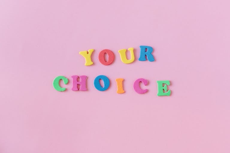 Vibrant foam letters spelling 'YOUR CHOICE' on a pink background. Perfect for concepts of decision-making.